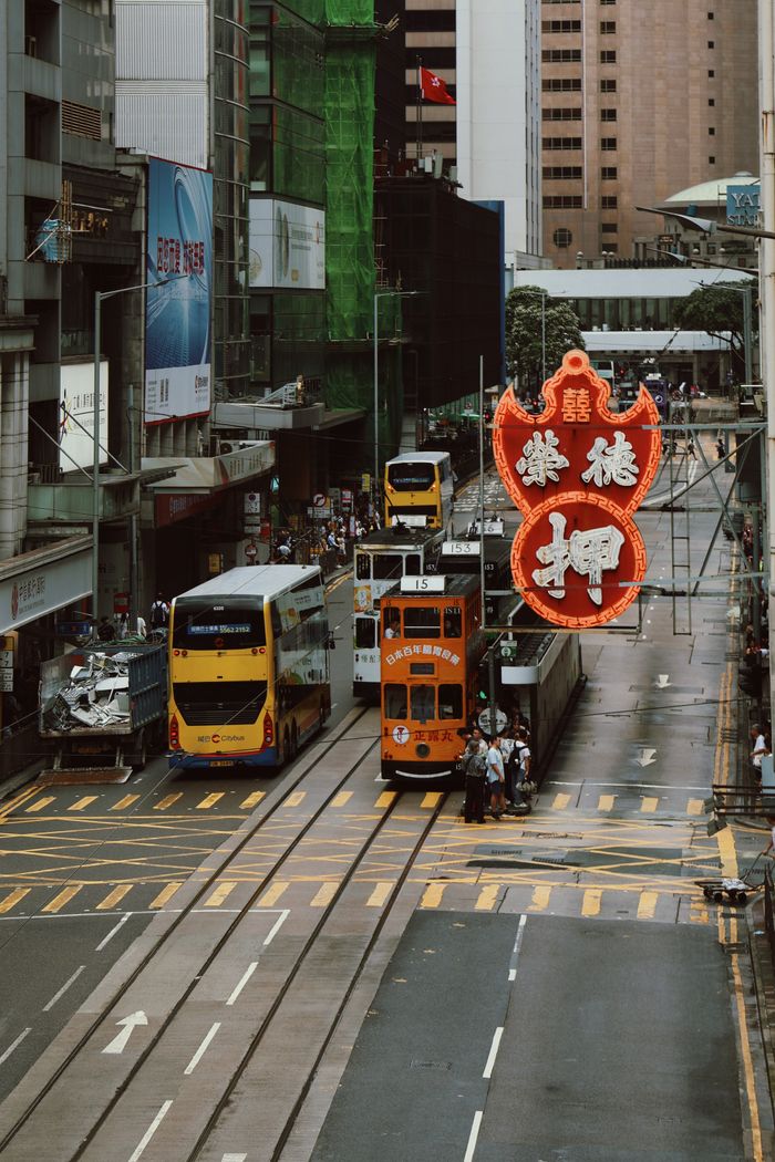 gallery-6 Vintage view of bustling Hong Kong street featuring colorful trams and iconic signage.