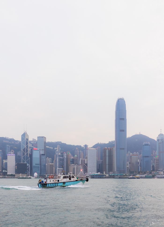 gallery-2 Elevated view of Hong Kong skyline featuring a ferry and harbor, showcasing iconic skyscrapers.